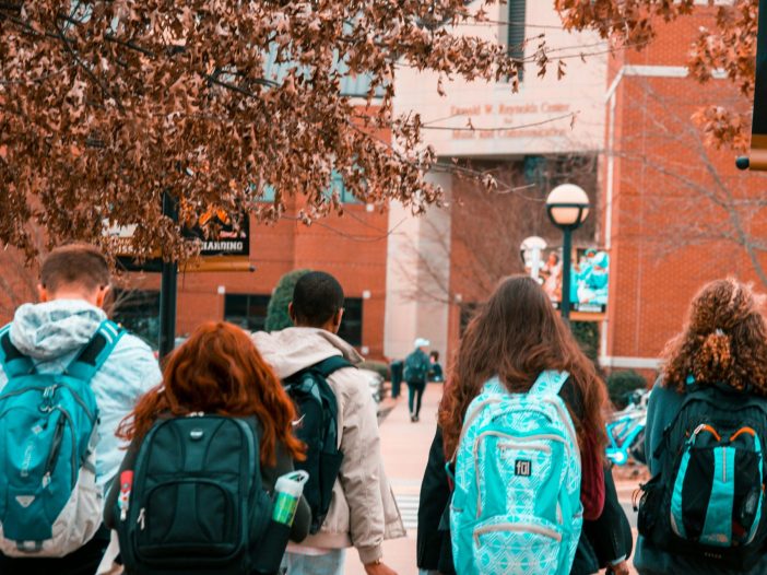 Group of college students walking on campus with backpacks during fall semester