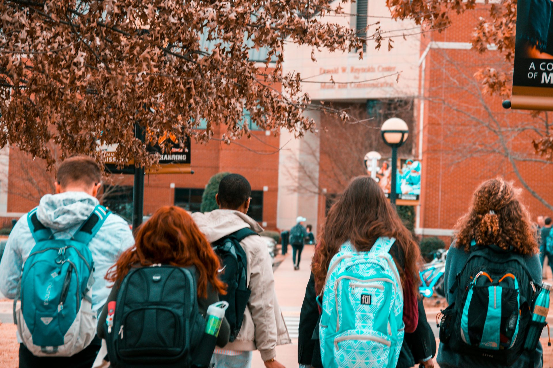 Group of college students walking on campus with backpacks during fall semester