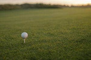 Golf ball on a white tee at sunrise on a golf course fairway