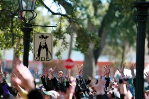 Crowd with raised hands gathered along a Mobile, Alabama Mardi Gras parade route near Joe Cain’s house.
