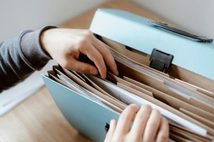 Hands organizing important personal documents in a file folder