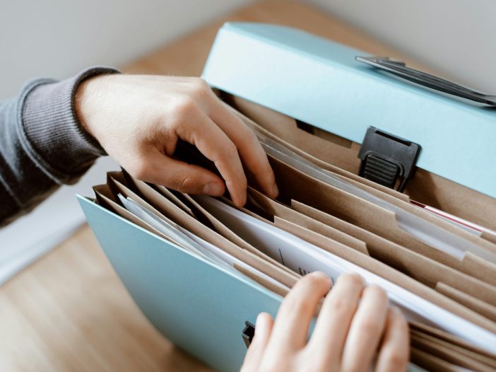 Hands organizing important personal documents in a file folder