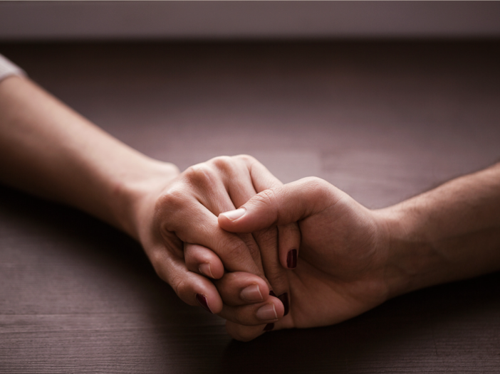 Close up of two people holding hands on a table