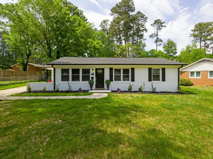Single-story brick home with a green lawn on a clear day in Alabama