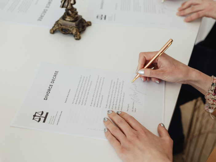 person signing divorce decree paperwork on desk