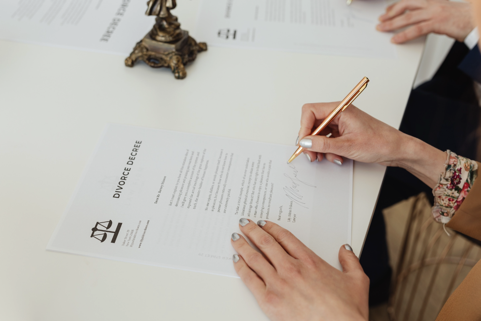 person signing divorce decree paperwork on desk