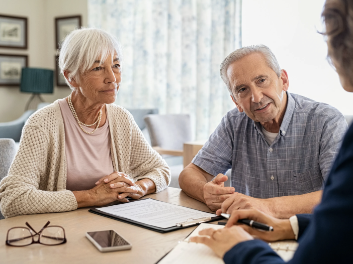 Two adults seated at a table reviewing documents together with an advisor.