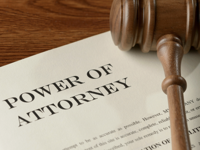 A power of attorney document on a wooden desk with a wooden gavel resting on top