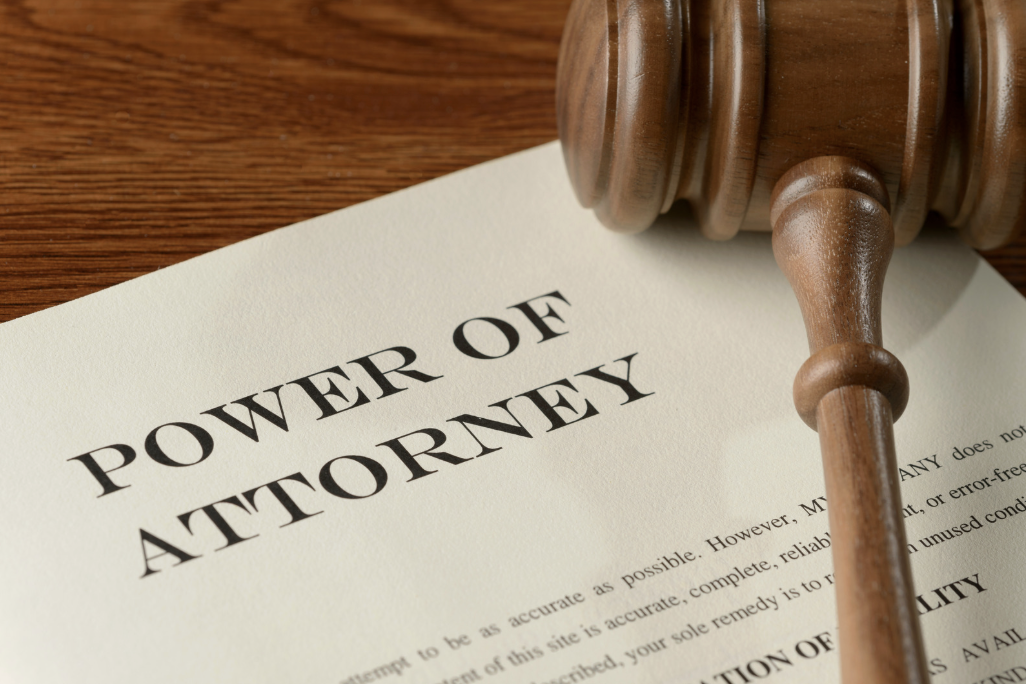 A power of attorney document on a wooden desk with a wooden gavel resting on top
