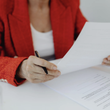 Person reviewing a stack of estate planning documents at a desk with a pen in hand