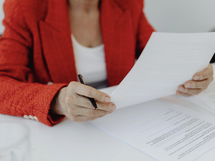 Person reviewing a stack of estate planning documents at a desk with a pen in hand