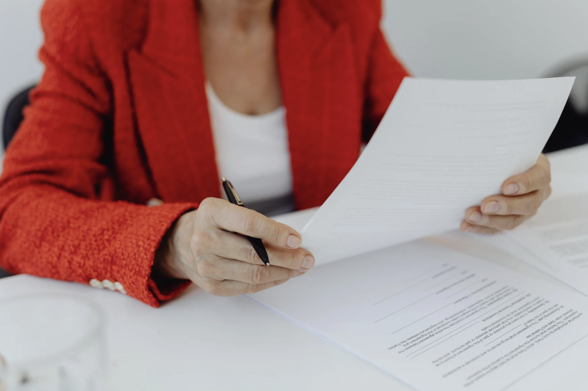 Person reviewing a stack of estate planning documents at a desk with a pen in hand