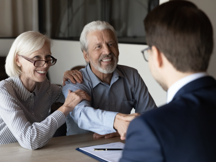 Financial advisor and clients reviewing estate planning documents at a desk