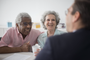 An advisor sitting across a desk from a married couple reviewing estate planning documents.