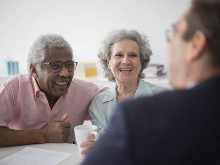 An advisor sitting across a desk from a married couple reviewing estate planning documents.