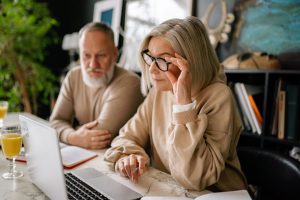 Older couple sitting together at a table, reviewing an online will on a laptop