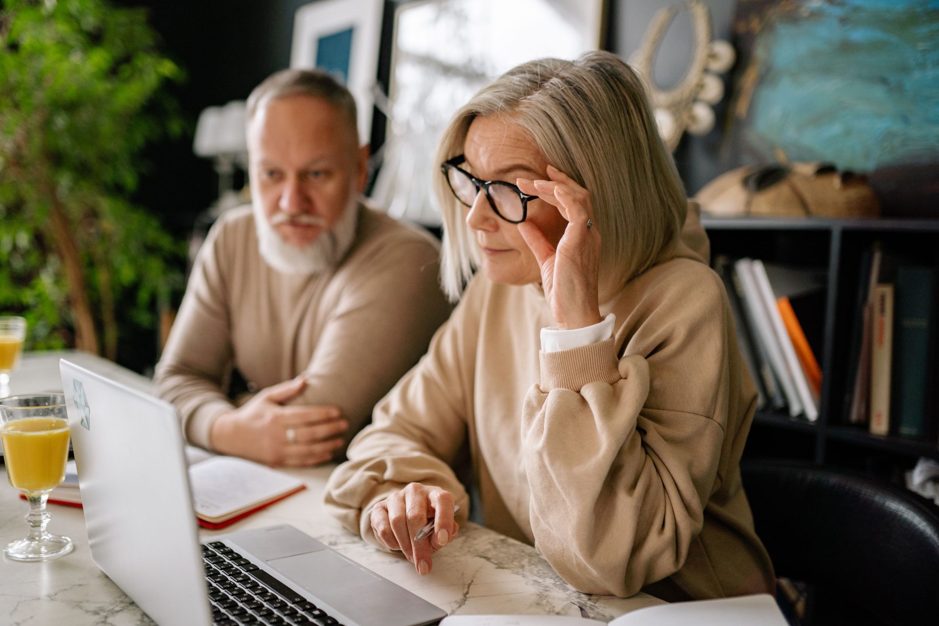 Older couple sitting together at a table, reviewing an online will on a laptop