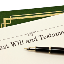 Last Will and Testament document with a fountain pen resting on top, next to a green folder with gold trim