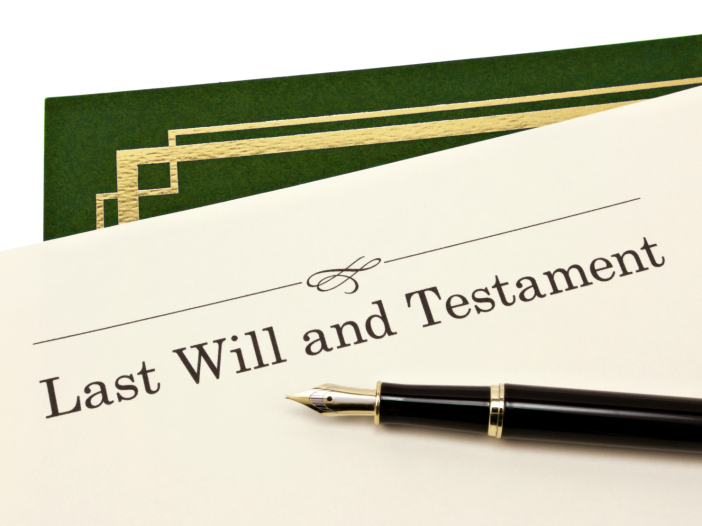 Last Will and Testament document with a fountain pen resting on top, next to a green folder with gold trim